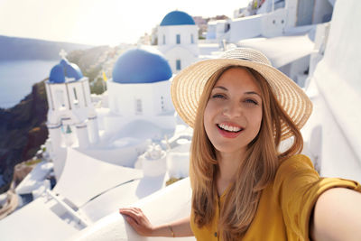 Hispanic beautiful fashion woman taking self portrait on sunset in santorini island, greece