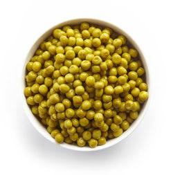 Bowl of green canned peas isolated on white background, top view