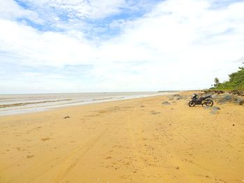 Motorcycle parked at beach against sky