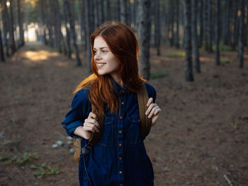 Portrait of smiling young woman standing in forest