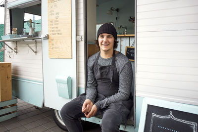 Portrait of smiling male owner sitting in food truck on street