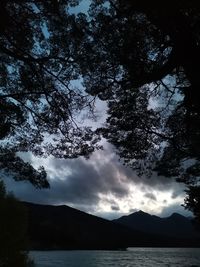 Scenic view of lake and silhouette mountains against sky at dusk