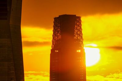 Low angle view of skyscrapers against orange sky