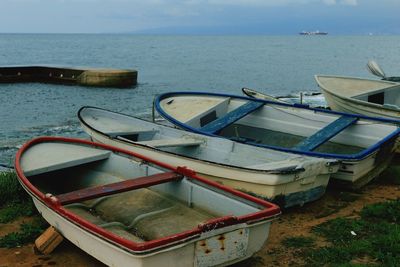 Boats moored at sea shore against sky