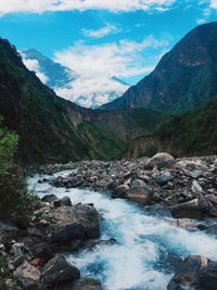 Scenic view of river stream amidst rocks against sky