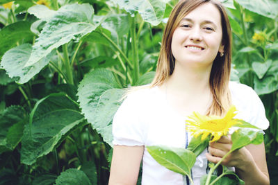 Portrait of smiling young woman standing against plants