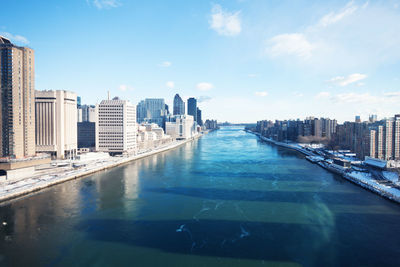 River amidst buildings in city against sky