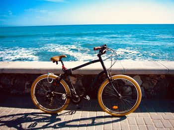 Bicycle by sea against sky