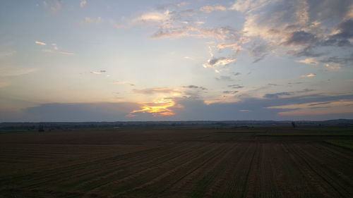 Scenic view of agricultural field against sky during sunset