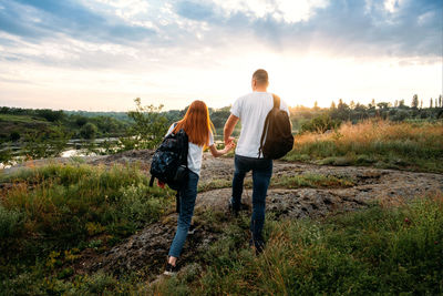 Rear view of couple standing on field against sky