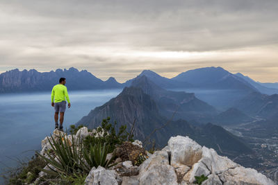 Rear view of man standing on mountain against sky