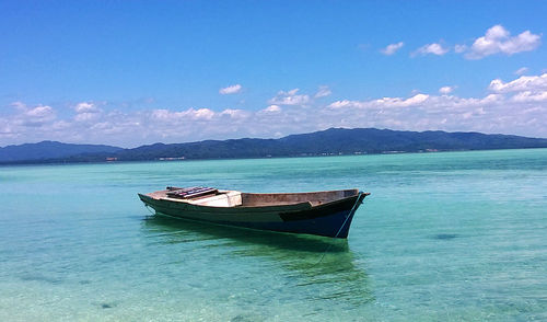 Boats in sea against cloudy sky