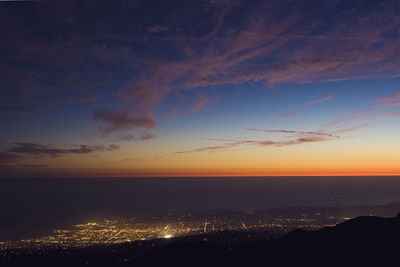 Aerial view of illuminated city against sky at dusk