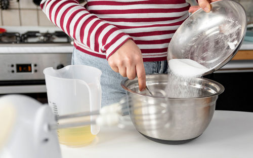 Midsection of woman mixing ingredients in mixing bowl. home, kitchen, cooking, baking.