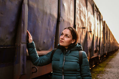 Portrait of a young woman standing against wall