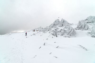 People hiking on snowcapped mountain against sky