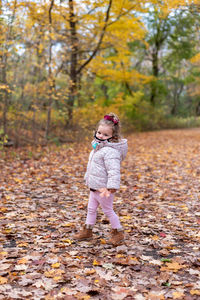 Full length of cute boy standing on tree during autumn