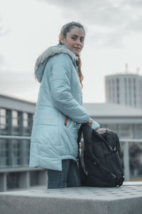 Portrait of young woman standing against buildings