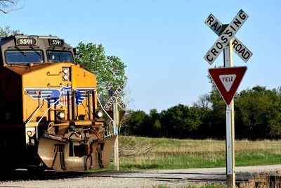 Information sign by railroad tracks against clear sky