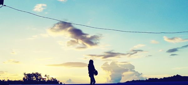 Silhouette woman standing against sky during sunset