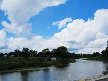 Scenic view of calm river against cloudy sky