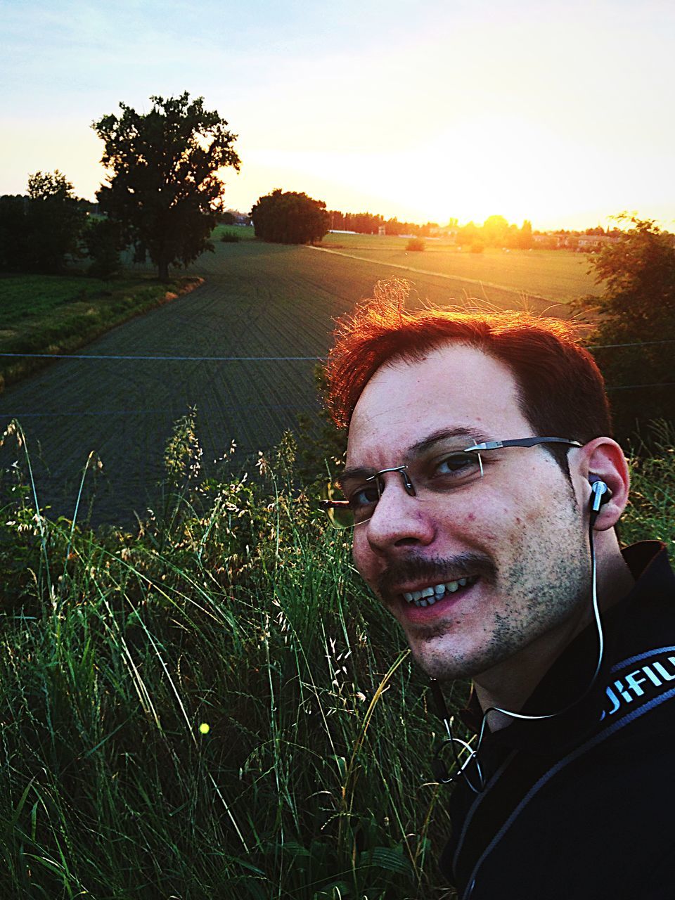 person, young adult, lifestyles, portrait, sunglasses, looking at camera, leisure activity, sunlight, headshot, young men, front view, smiling, sky, sun, casual clothing, clear sky, field, tree