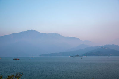 Scenic view of sea and mountains against clear sky