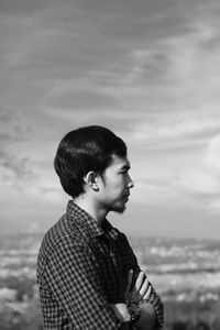 Side view of young man looking at sea against sky