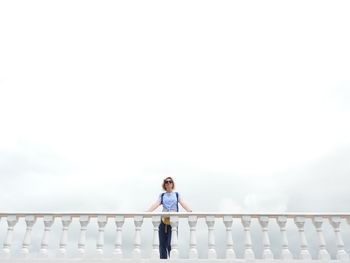 Full length of woman standing on railing against sky