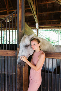 Smiling woman standing with horse in stable