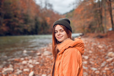 Portrait of smiling young woman standing on land during autumn