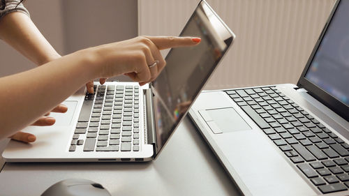 Cropped hands working over laptop at desk in office