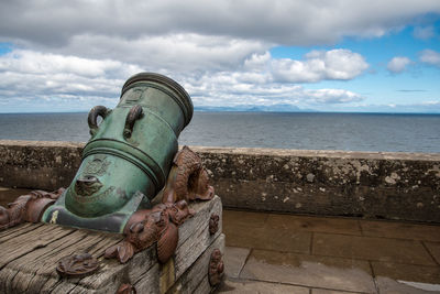 Old metal by sea against sky
