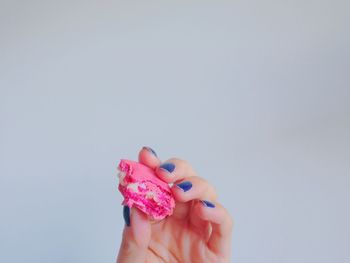 Cropped image of hand holding macaroon against gray background