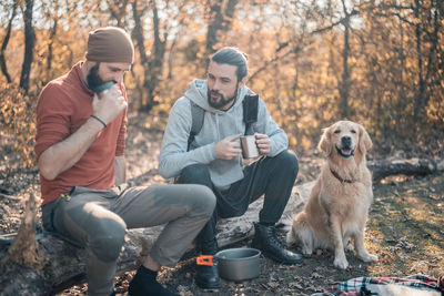 Full length of men sitting dog against trees