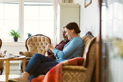 Side view of woman sitting on seat at home