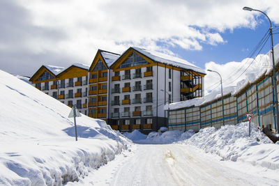 Snow covered houses by buildings against sky