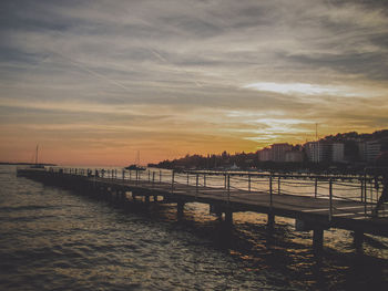 Scenic view of sea by buildings against sky during sunset