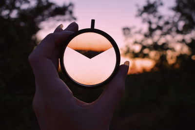 Person holding sunglasses against sky