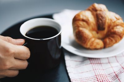 Close-up of hand holding coffee cup on table