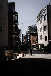 Cars on city street by buildings against sky