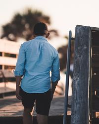 Rear view of man walking on wooden walkway