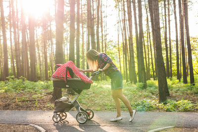 Woman riding bicycle on road amidst trees in forest