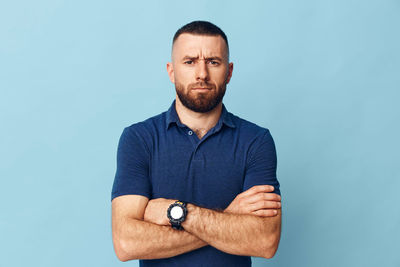 Portrait of young man standing against blue background