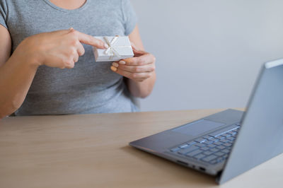 Midsection of woman using mobile phone while sitting on table