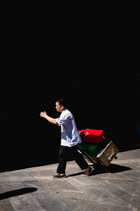 Side view of a young man standing against black background