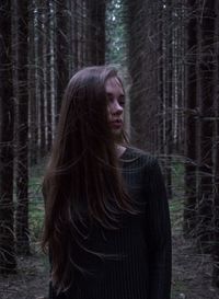 Woman standing against trees in forest