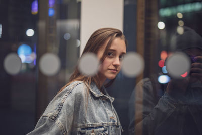 Portrait of young woman seen through glass window