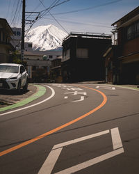 Road by buildings against sky in city