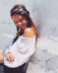 Smiling woman leaning on white wall